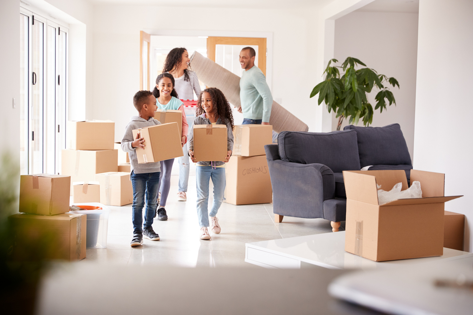 Smiling Family Carrying Boxes into New Home on Moving Day